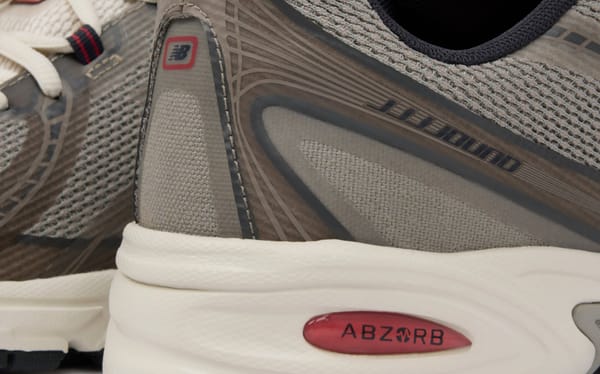 Heel and lateral detail of the JJJJound x New Balance 740N "Mushroom" showing the taupe fused overlays, JJJJound heel wordmark, cream midsole and red ABZORB unit