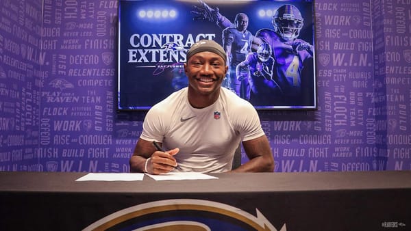 Zay Flowers signing his contract extension at a Baltimore Ravens podium