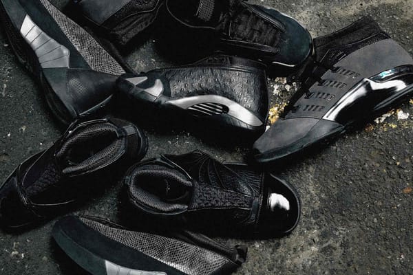 The Air Jordan Black Pack — Air Jordan 14 Low, 15, 16 and 17 Low in black exotic-texture materials — on a dark textured surface
